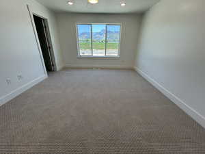 Unfurnished room featuring baseboards, light carpet, and a mountain view