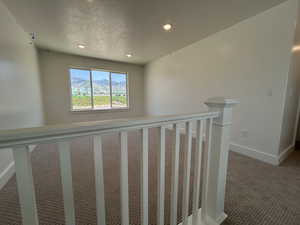 Hall featuring carpet floors, recessed lighting, baseboards, an upstairs landing, and a textured ceiling