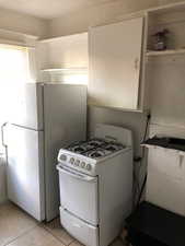 2nd floor Kitchen featuring white appliances, light tile patterned flooring, open shelves, and white cabinetry