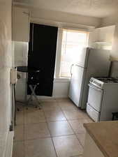 2nd floor Kitchen with white range with gas stovetop, a textured ceiling, and light tile patterned floors