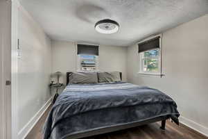 Bedroom featuring baseboards, a textured ceiling, and wood finished floors