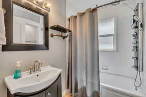 Bathroom with shower / bathtub combination with curtain and vanity