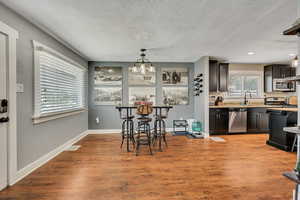 Dining room with a textured ceiling, wood finished floors, baseboards, and recessed lighting