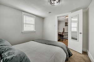 Bedroom with multiple windows, a desk, and carpet floors