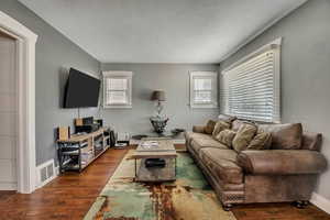 Living room with wood finished floors, a textured ceiling, healthy amount of natural light, and baseboards