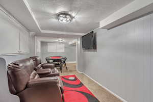 Living area featuring a textured ceiling, carpet floors, and baseboards