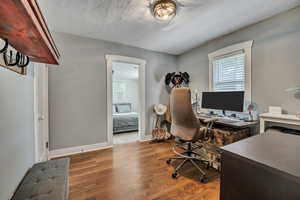 Home office featuring wood finished floors, a textured ceiling, and baseboards