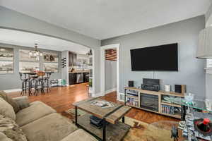 Living area featuring wood finished floors, arched walkways, a chandelier, and baseboards