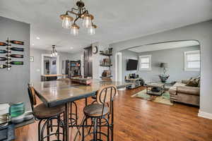 Dining room featuring arched walkways, wood finished floors, a textured ceiling, baseboards, and a chandelier