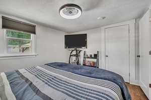 Bedroom with a textured ceiling and wood finished floors