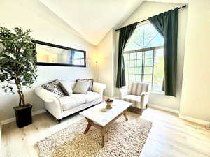 Living room with wood finished floors, vaulted ceiling, and baseboards