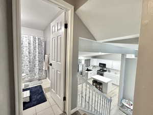 Bathroom featuring a sink, a textured ceiling, toilet, tile patterned floors, and vaulted ceiling