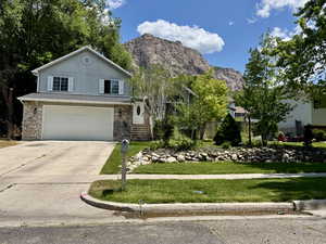 View of front of house with a garage, driveway, stone siding, and a mountain view
