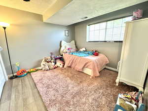 Bedroom with a textured ceiling, wood finished floors, and baseboards