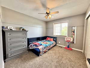 Bedroom with carpet floors, a textured ceiling, baseboards, and a ceiling fan