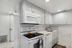 This updated Kitchen modern colors, quarts countertops, white appliances, an over sized stainless steel sink, light durable tile patterned flooring.