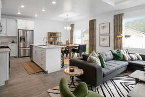 Living area with a raised ceiling, a chandelier, plenty of natural light, recessed lighting, and light wood-style floors