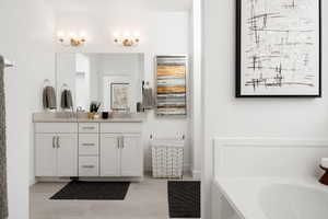 Bathroom with double vanity, a bathtub, baseboards, and tile patterned floors