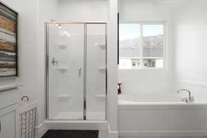 Bathroom featuring a stall shower, a bath, and a mountain view