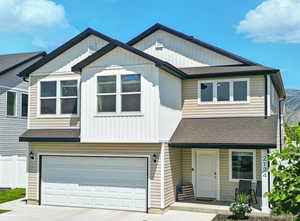 Townhome / multi-family property featuring a shingled roof, an attached garage, and driveway