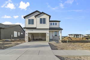 View of front of house with concrete driveway, an attached garage, stone siding, and stucco siding