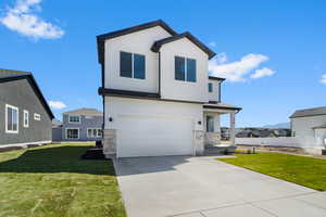 View of front facade with an attached garage, driveway, a residential view, stucco siding, and a front lawn