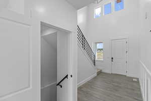 Entrance foyer with wood finished floors, plenty of natural light, baseboards, stairway, and a towering ceiling