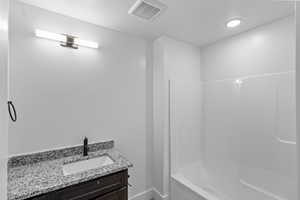 Full bath with vanity, shower / tub combination, and baseboards