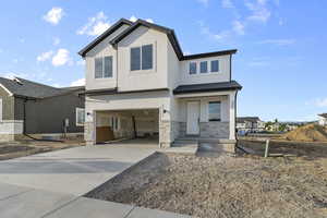 View of front of property with a garage, stone siding, concrete driveway, and stucco siding