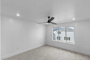 Primary bedroom with large windows, light carpet, a ceiling fan, and recessed lighting