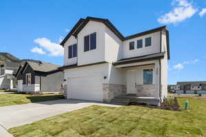 View of front of property featuring stone siding, a front yard, stucco siding, and an attached garage
