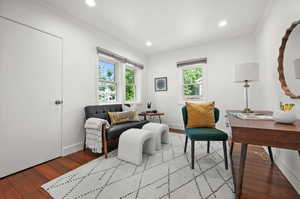 Living area featuring wood finished floors, crown molding, recessed lighting, and baseboards