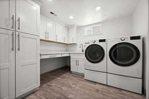 Washroom featuring washer and clothes dryer, cabinet space, wood finished floors, and recessed lighting