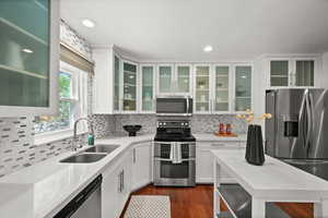 Kitchen featuring appliances with stainless steel finishes, a sink, white cabinetry, backsplash, and recessed lighting