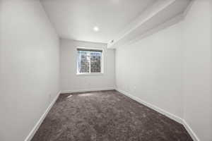 Empty room with dark colored carpet, baseboards, and recessed lighting