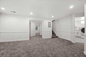 Basement featuring carpet, washer / dryer, recessed lighting, arched walkways, and a sink