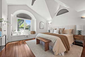 Bedroom featuring vaulted ceiling, wood-type flooring, and arched walkways