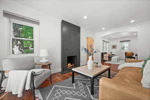 Living area with a fireplace, wood finished floors, crown molding, arched walkways, and recessed lighting
