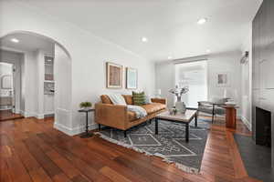 Living room with baseboards, hardwood / wood-style flooring, arched walkways, ornamental molding, and recessed lighting