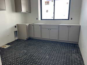 Laundry area with cabinet space and dark carpet