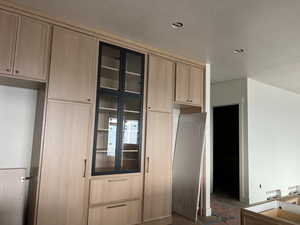 Kitchen with light brown cabinets, glass insert cabinets, a textured ceiling, and dark wood finished floors