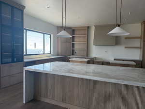 Kitchen with pendant lighting, ventilation hood, dark wood finished floors, a kitchen island, and open shelves