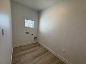 Laundry area featuring electric dryer hookup, light wood-style floors, baseboards, and hookup for a washing machine