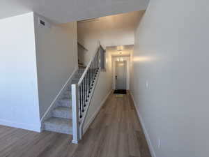 Stairway with wood finished floors, baseboards, and a textured ceiling