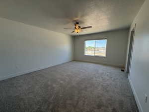 Spare room featuring a ceiling fan, a textured ceiling, light colored carpet, and baseboards