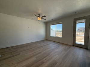 Empty room featuring a textured ceiling, wood finished floors, baseboards, and ceiling fan