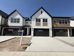 View of front of home with a garage, concrete driveway, and brick siding