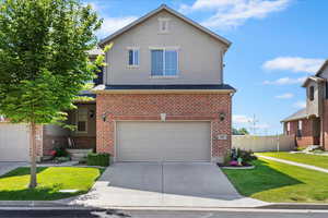Traditional home with an attached garage, brick siding, and concrete driveway