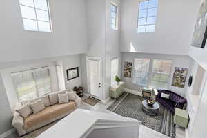 Living room featuring a towering ceiling, baseboards, and wood finished floors