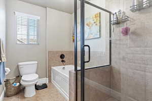 Bathroom featuring a garden tub, toilet, a stall shower, tile patterned floors, and baseboards